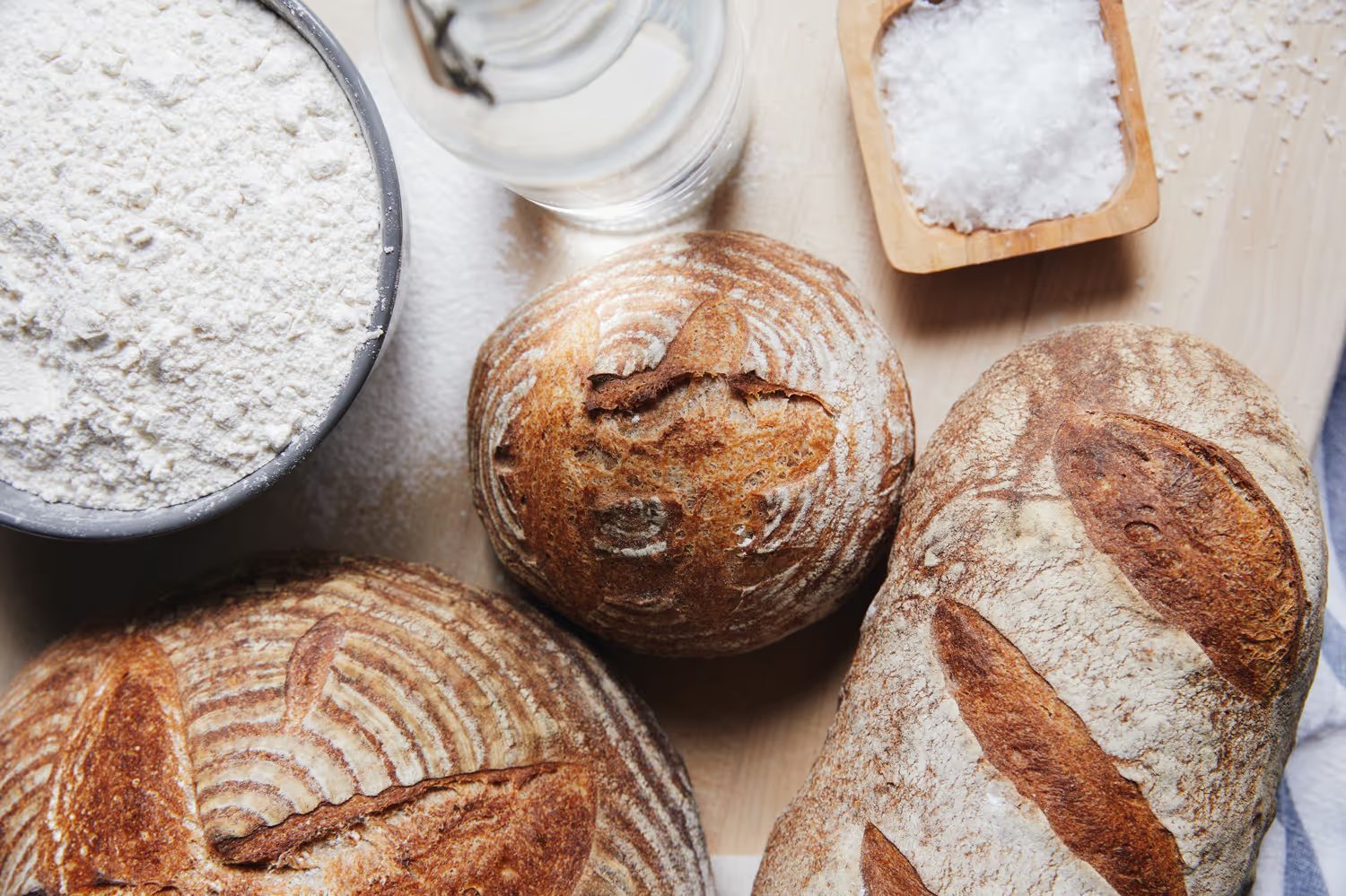 Fresh sourdough loaves beside bowls of flour and salt